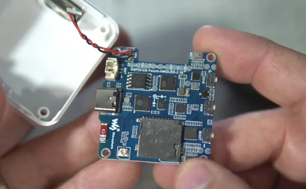 Interno della custodia con scheda ESP32-C6, batteria e componenti elettronici.